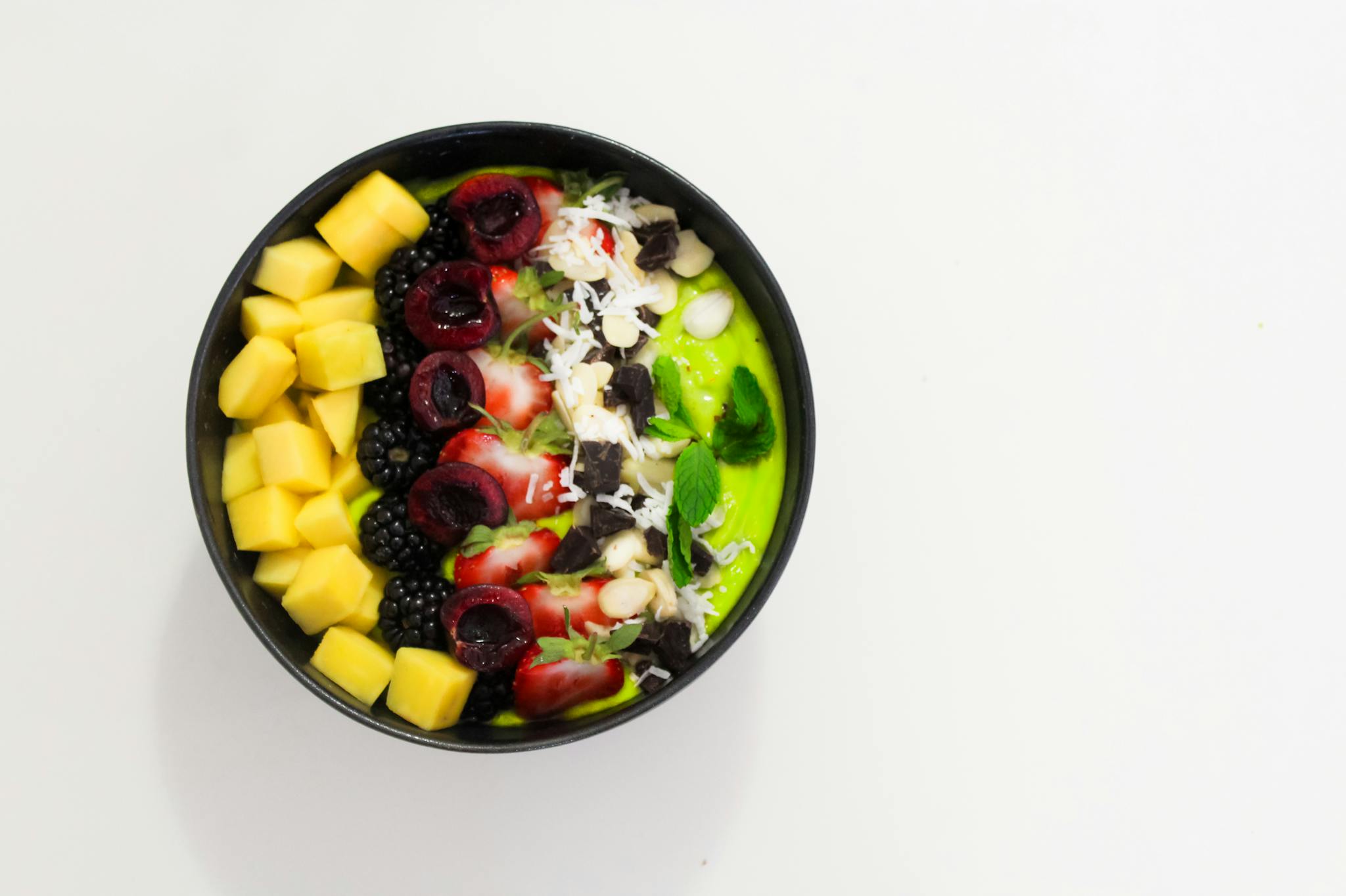 Delicious super food mixed fruit bowl with mango, blackberry, and cherry atop a creamy base. Perfect for a healthy diet.