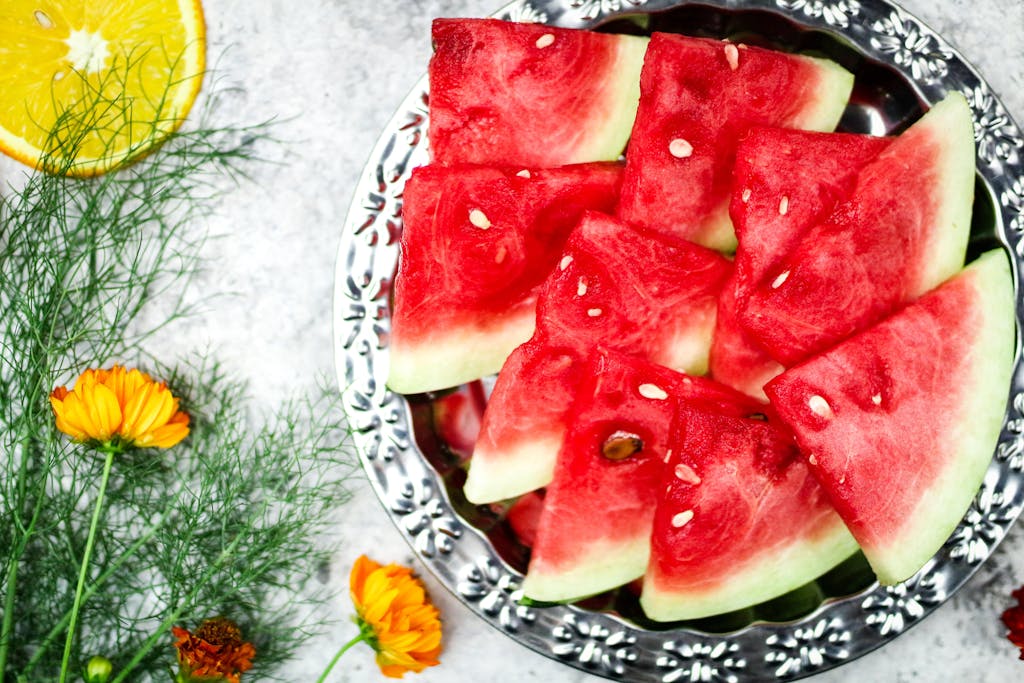 Juicy, sliced watermelon on a silver plate with floral accents, perfect for healthy summer eating.